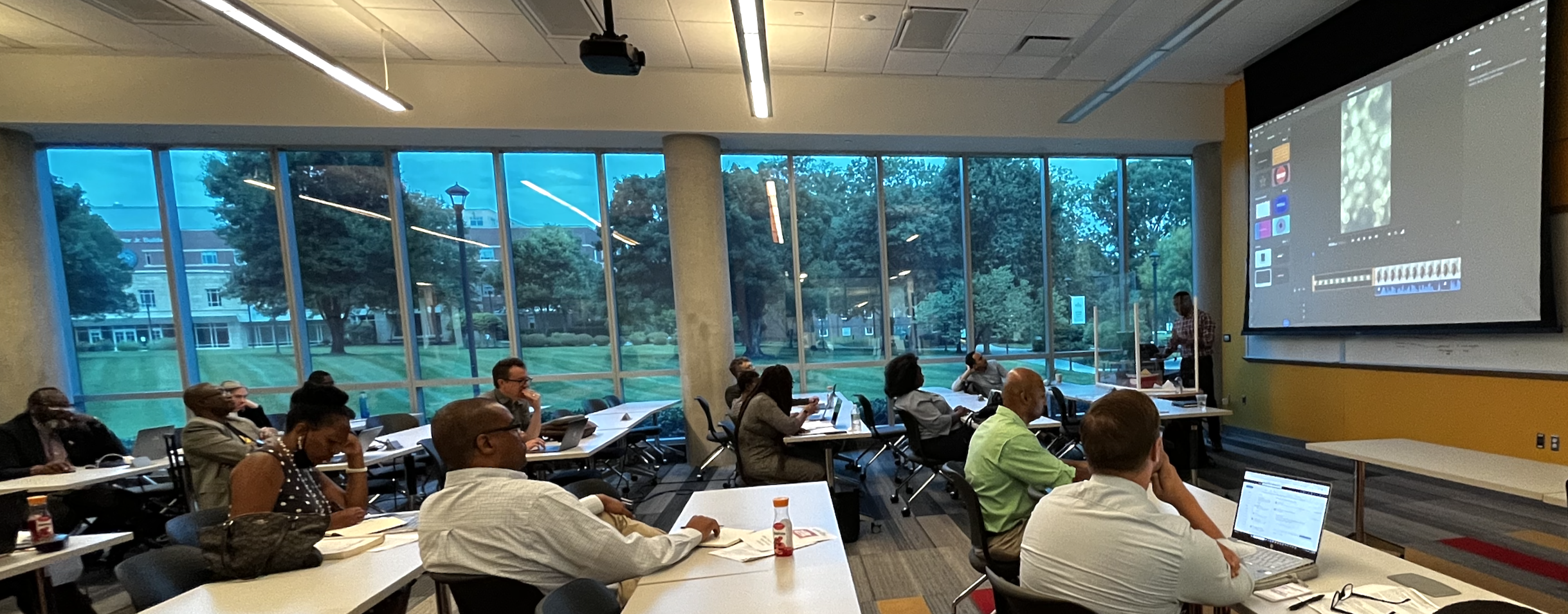 Classroom with windows in the background and a projection screen duing a faculty training session.