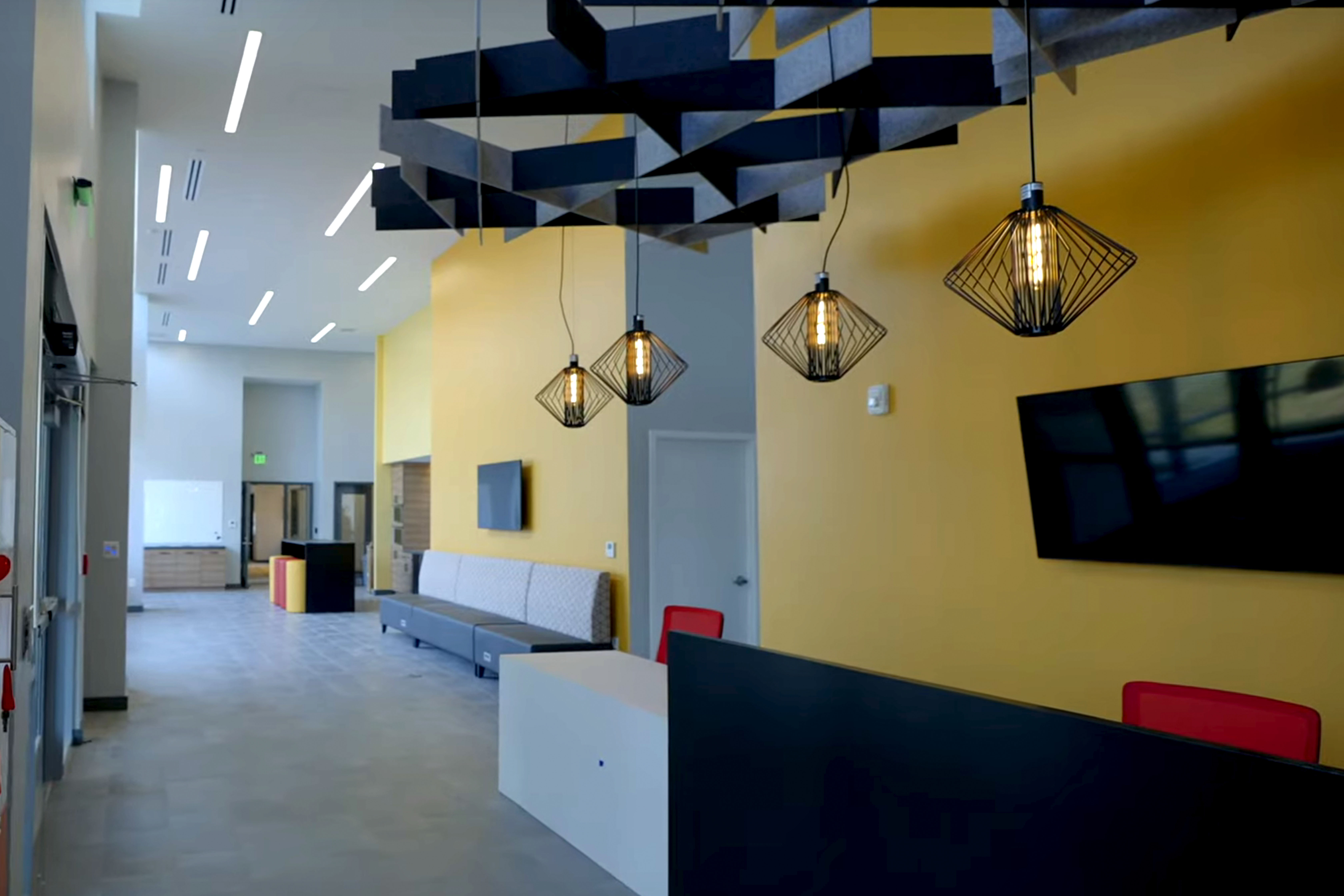 View of open seating area with red chairs, sofa and light fixtures. 