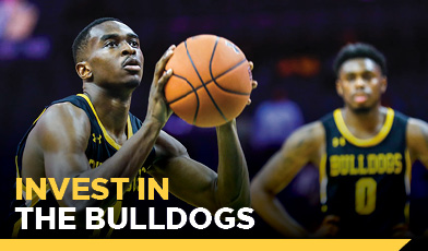 bastketball player setting up to shoot the ball with another player watching in the background. text: Invest in the Bulldogs