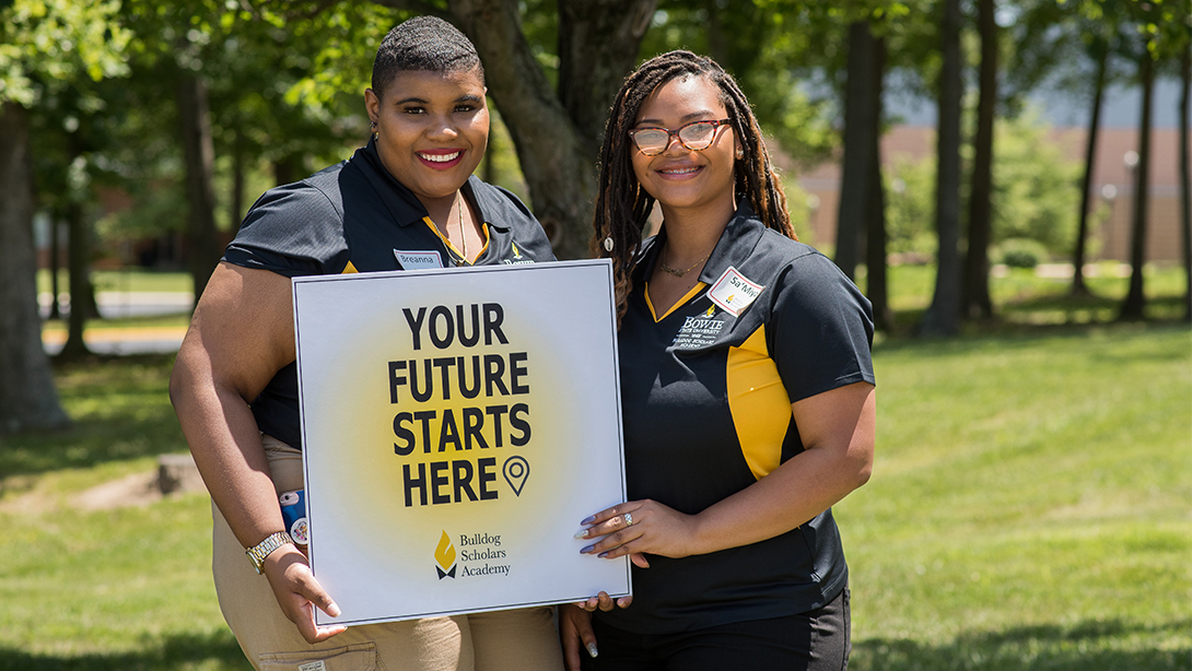 Two mentors hold a sign that reads your future starts here