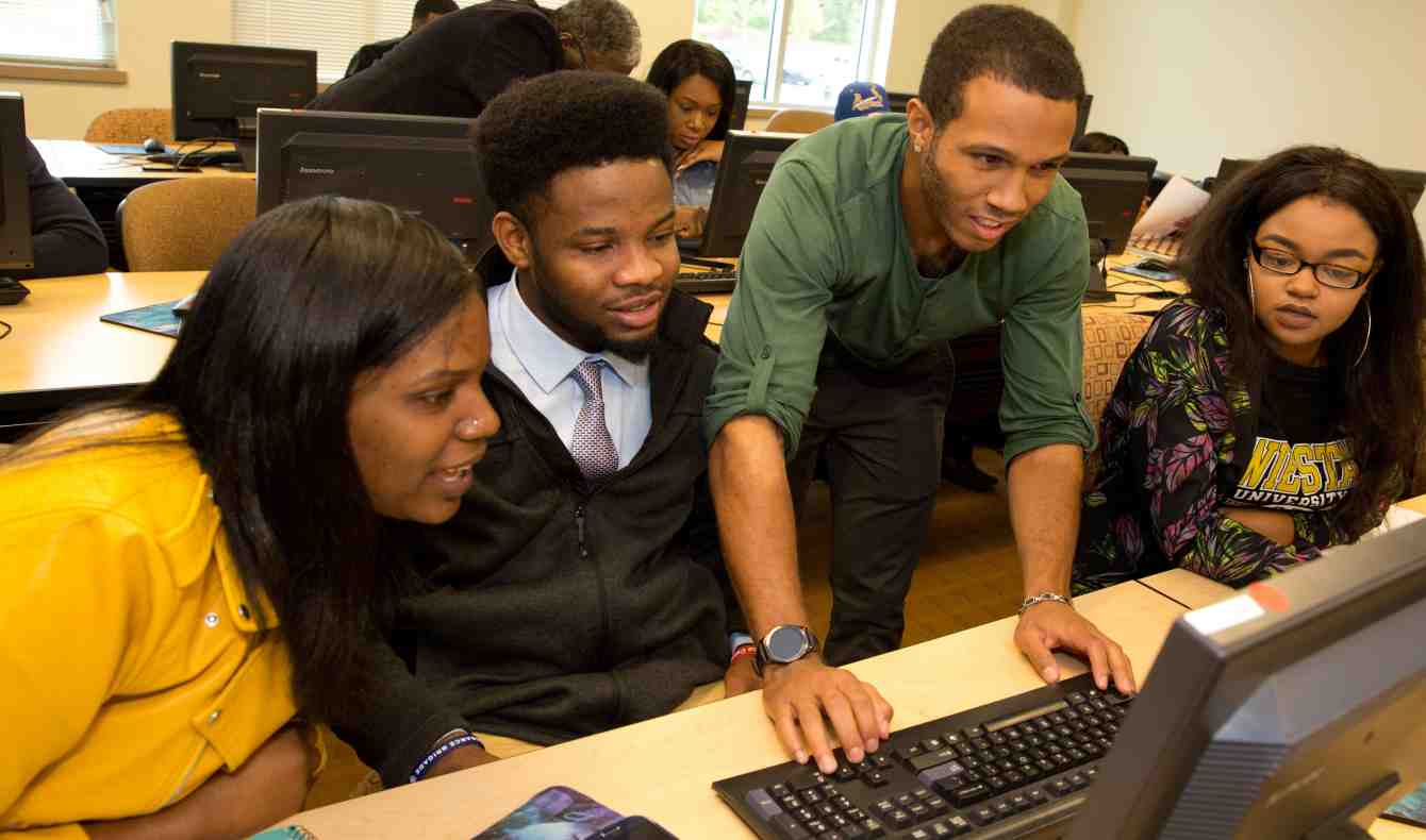 Four Students Huddled Around a Computer Screen