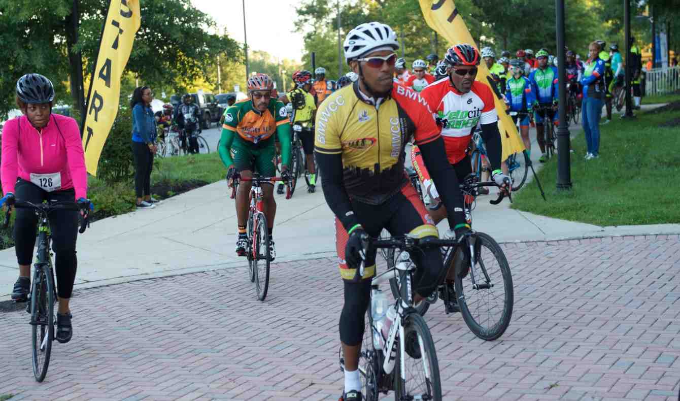 President Breaux Leads a Group of Cyclists in Bike Tour