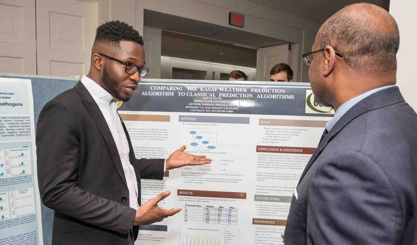 Jesuye David presents his poster to a professional at the Posters on the Hill
